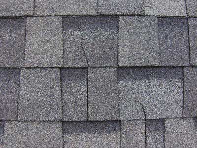Cracked asphalt shingles sagging as a result of damage