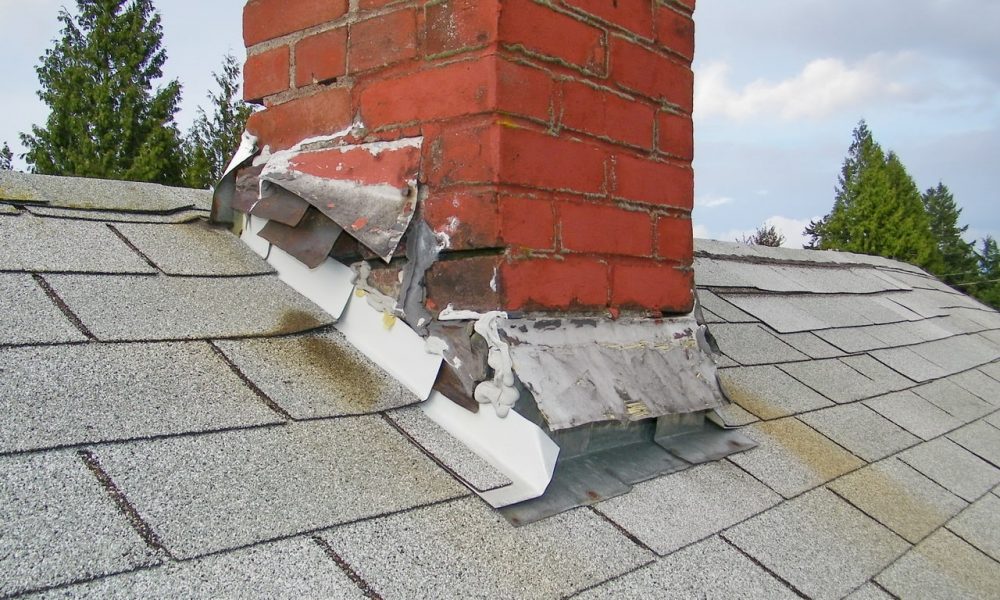 Signs of leaks, rusting, and broken shingles around flashing on a chimney