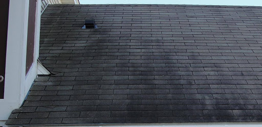 An asphalt shingle roof with dark stains from leaks and moisture