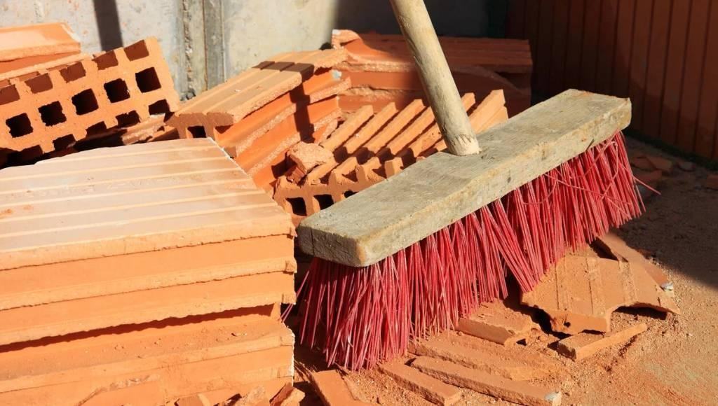 A broom sits among freshly removed roof tiles