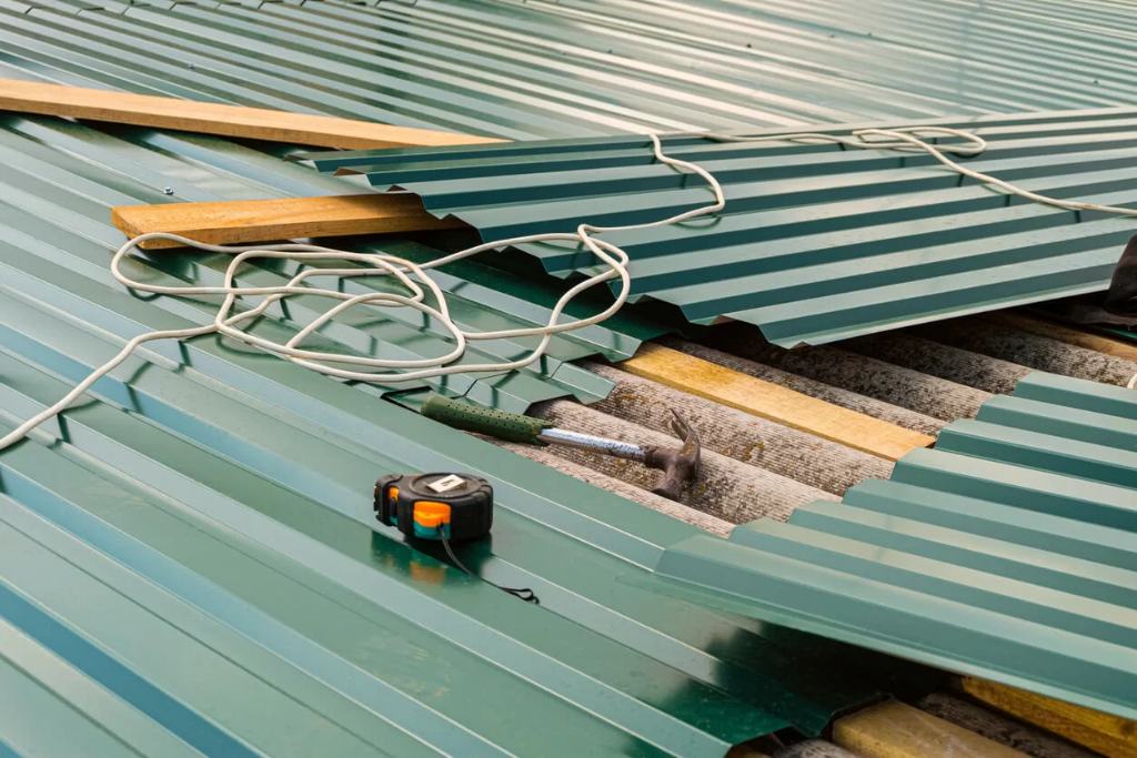 Metal roofing panels lay on a roof in the middle of a replacement job