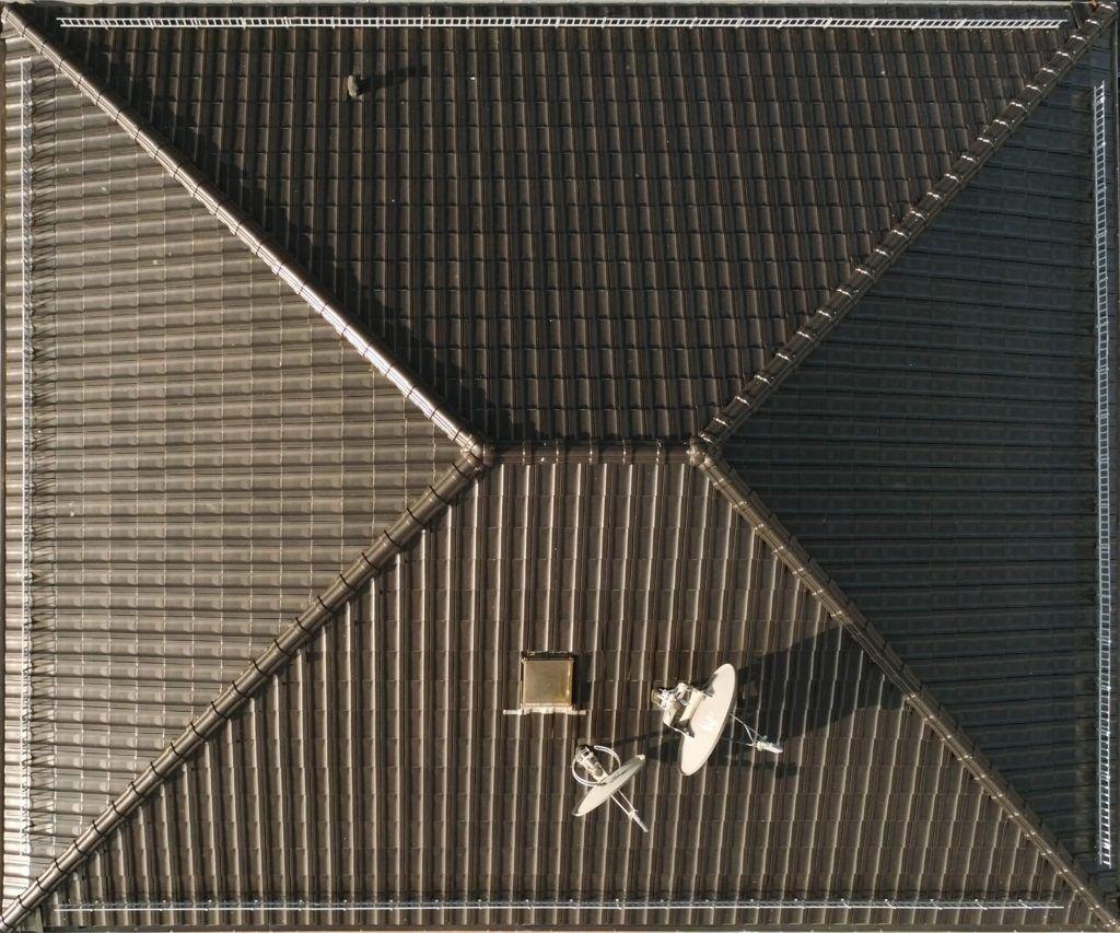 A hipped roof on a home with two satellite dishes and a skylight.