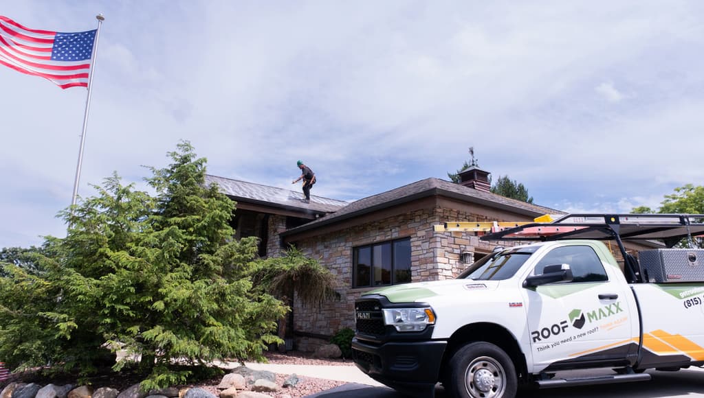 A Roof Maxx truck parked in front of a customer's home