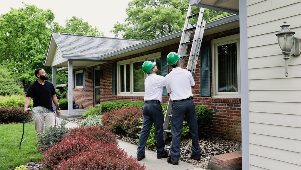 Two Roof Maxx representatives set up a ladder to apply a patented solution to a customer's roof.