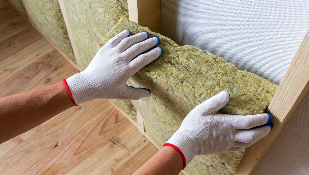 Homeowner installing insulation to help protect roof and extend shingle lifespan.