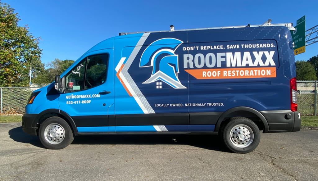 A blue branded Roof Maxx van with the words "Don't Replace. Save Thousands. Roof Maxx Roof Restoration" on the side.