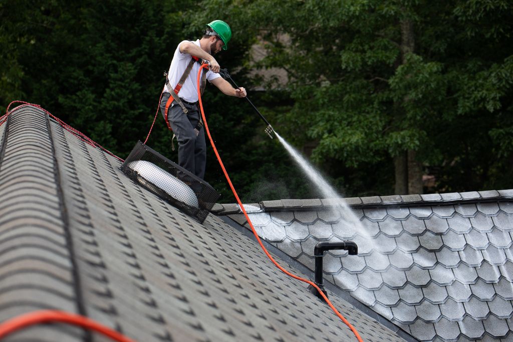 A Roof Maxx dealer sprays the treatment on an asphalt shingle roof.