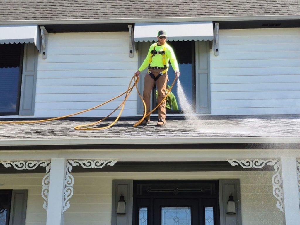 Roofing professional using applicator to spray asphalt shingles with Roof Maxx so homeowner can save money instead of replacing their roof