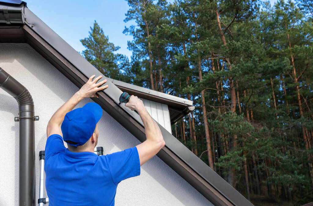 A roofer installs metal drip edge on a residential roof.